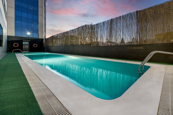 Una piscina al aire libre de temporada, sombrillas, tumbonas