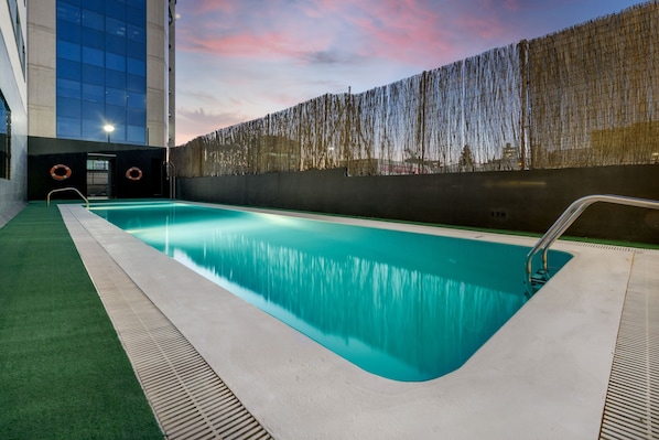 Una piscina al aire libre de temporada, sombrillas