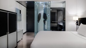 A modern hotel room with a large bed, a wardrobe, a glass partition, and a bathroom visible through the partition. - AC Hotel Murcia by Marriott (Murcia)