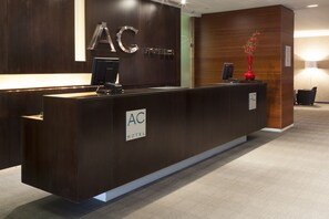 A reception desk with a sign reading "AC Hotel."