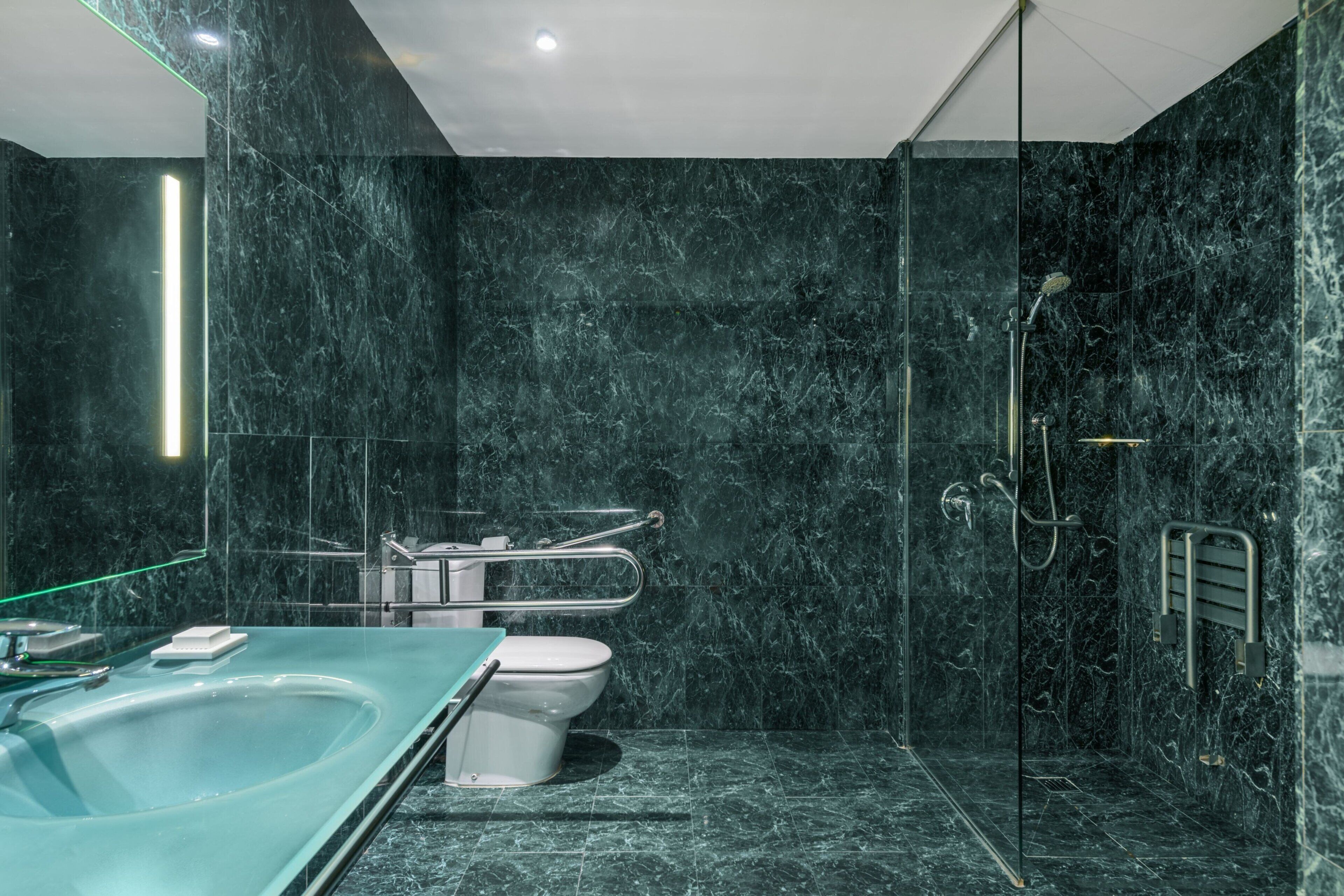 Ein modernes Badezimmer mit einer begehbaren Glasdusche, einer freistehenden Badewanne und einem WC.