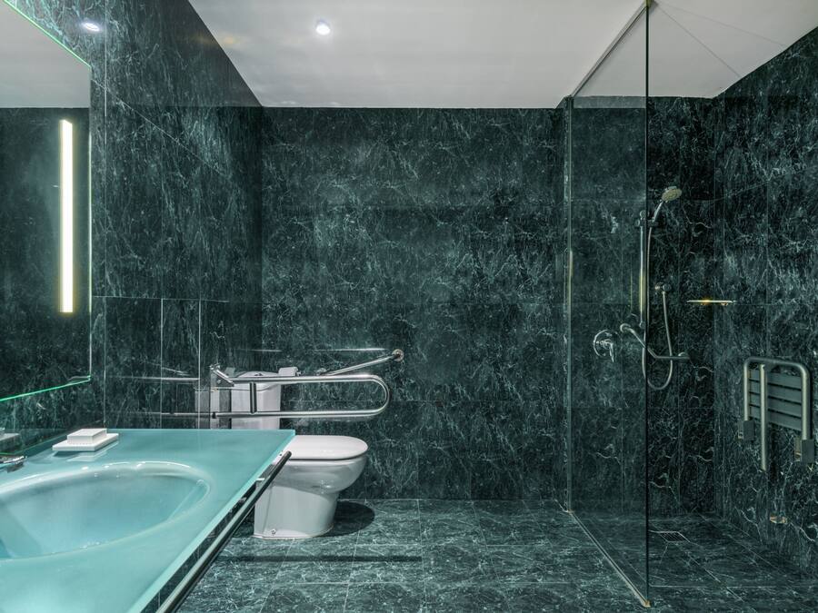 Un baño moderno con ducha envuelta en cristal, una bañera independiente y un inodoro.