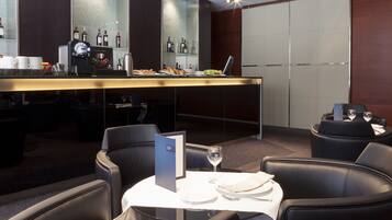 A modern bar area with a coffee machine, wine bottles, and a menu stand.