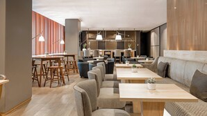 Un intérieur moderne avec des espaces aménagés pour s  ’asseoir, des tables et des luminaires suspendus.