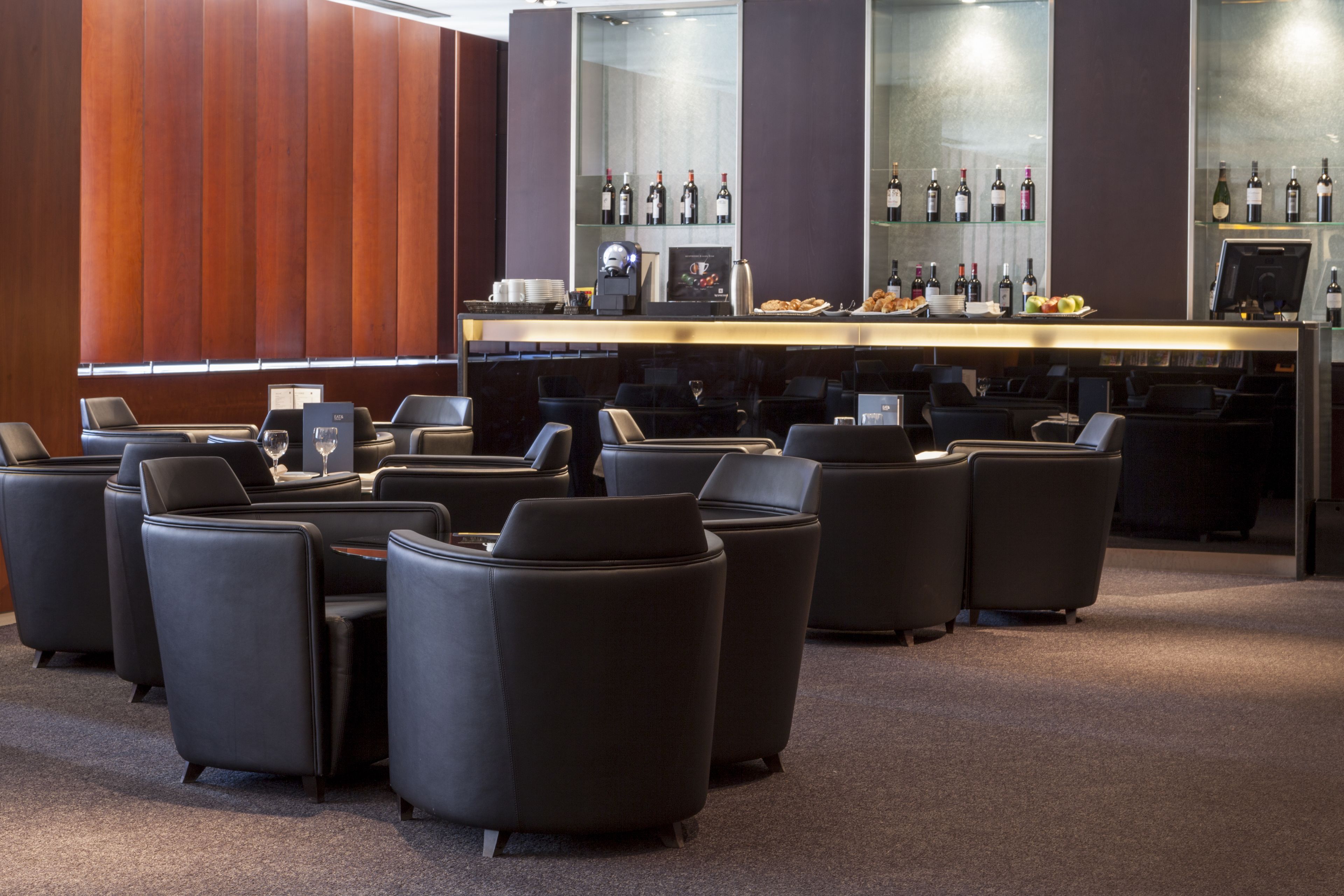Un área de bar moderna con asientos de cuero y una vitrina de vinos.