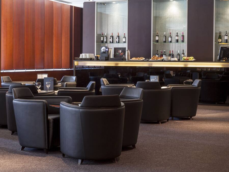 Un área de bar moderna con asientos de cuero y una vitrina de vinos.