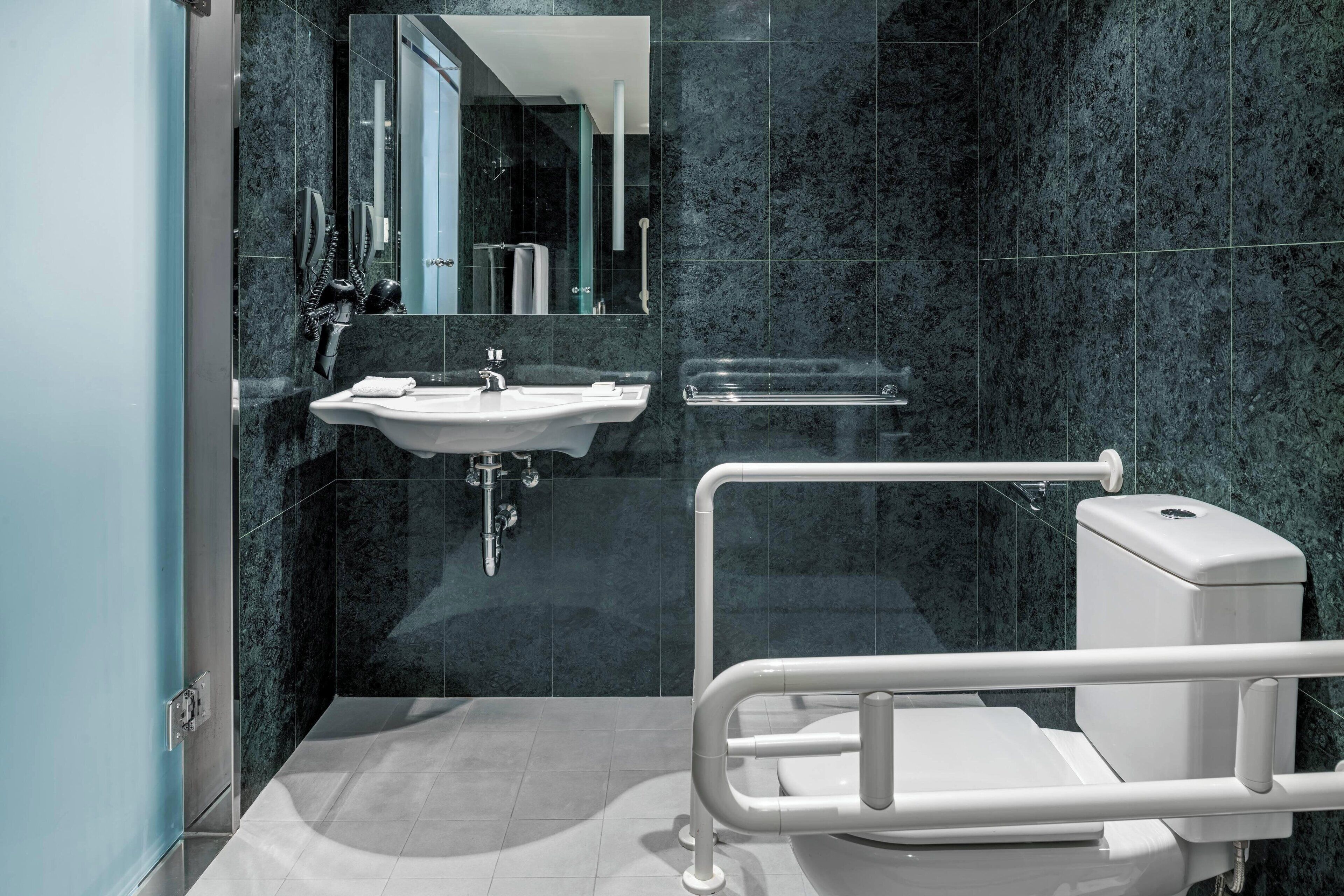 Et moderne badeværelse med en hvid vask, brusekabine i glas og et hvidt toilet.