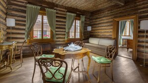 Ein Holzblockhaus-Interieur mit Holztisch, Stühlen, einer Couch und Vorhängen.