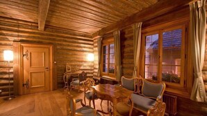 Ein Holzblockhaus-Innenraum mit einem Holzesstisch, Stühlen und einem Kamin.