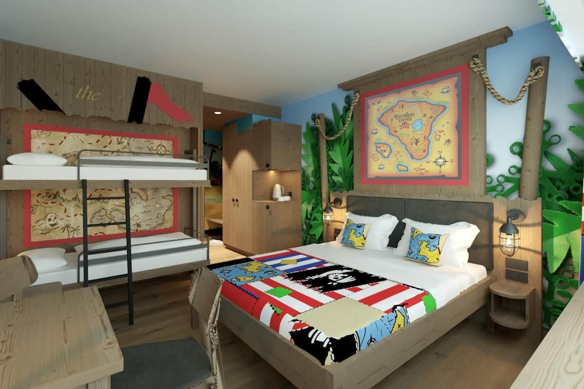 A bedroom with a bunk bed, a desk, and a bed with a colorful quilt.