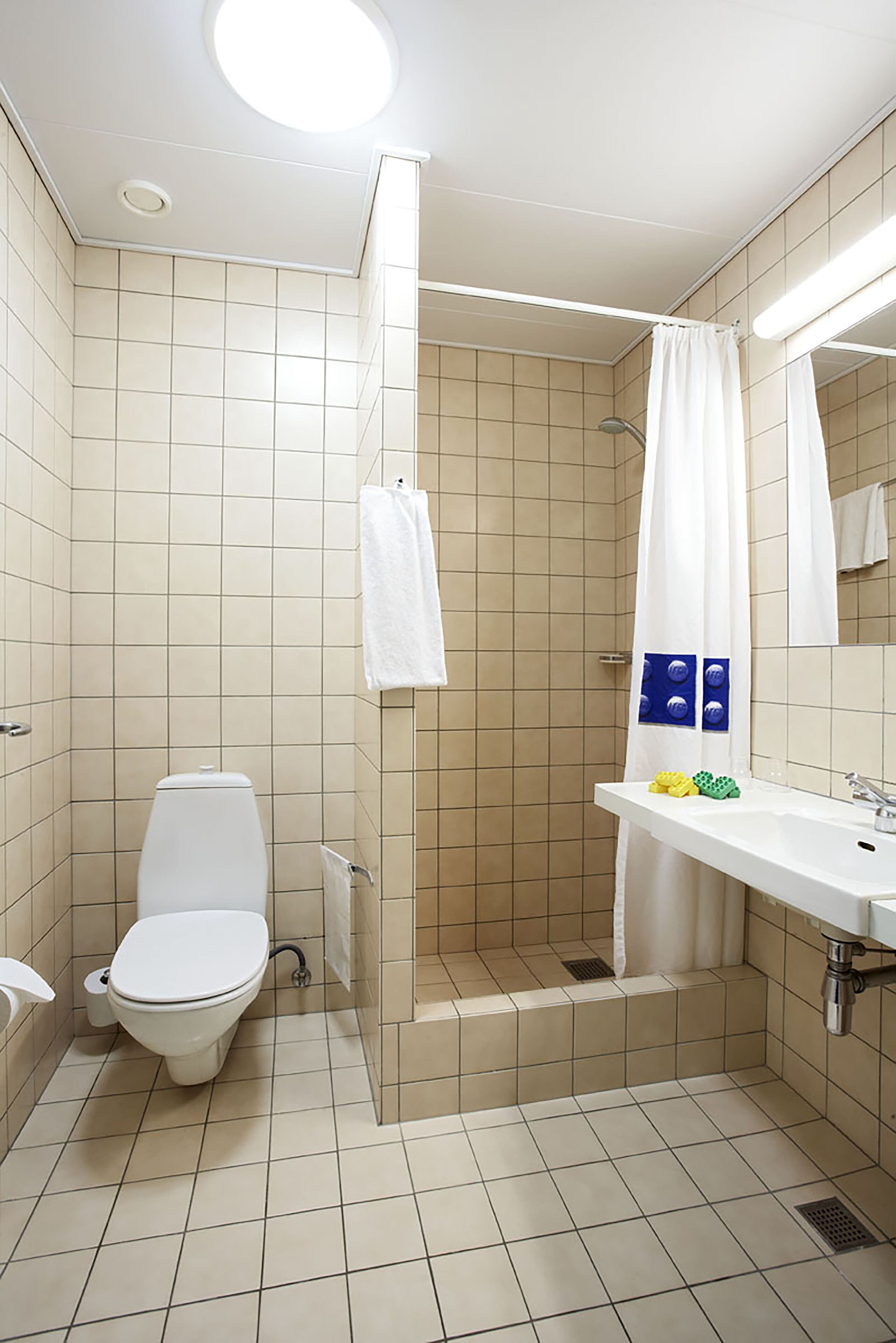 Ein Badezimmer mit Toilette, Waschbecken, Dusche und gefliesten Wänden.