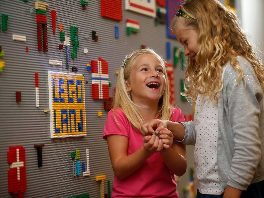 A room with a LEGO wall display and a bed.