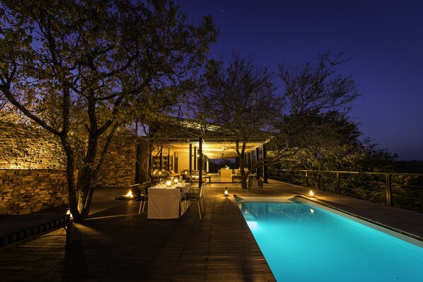 Una piscina al aire libre, sombrillas, sillones reclinables de piscina