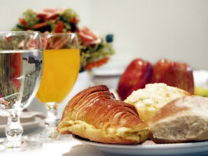 A plate with a croissant, a piece of bread, and a glass of orange juice.