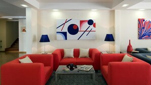 A modern living room with red sofas, a glass coffee table, and abstract art on the walls. - Cruz Alta (Ourem)