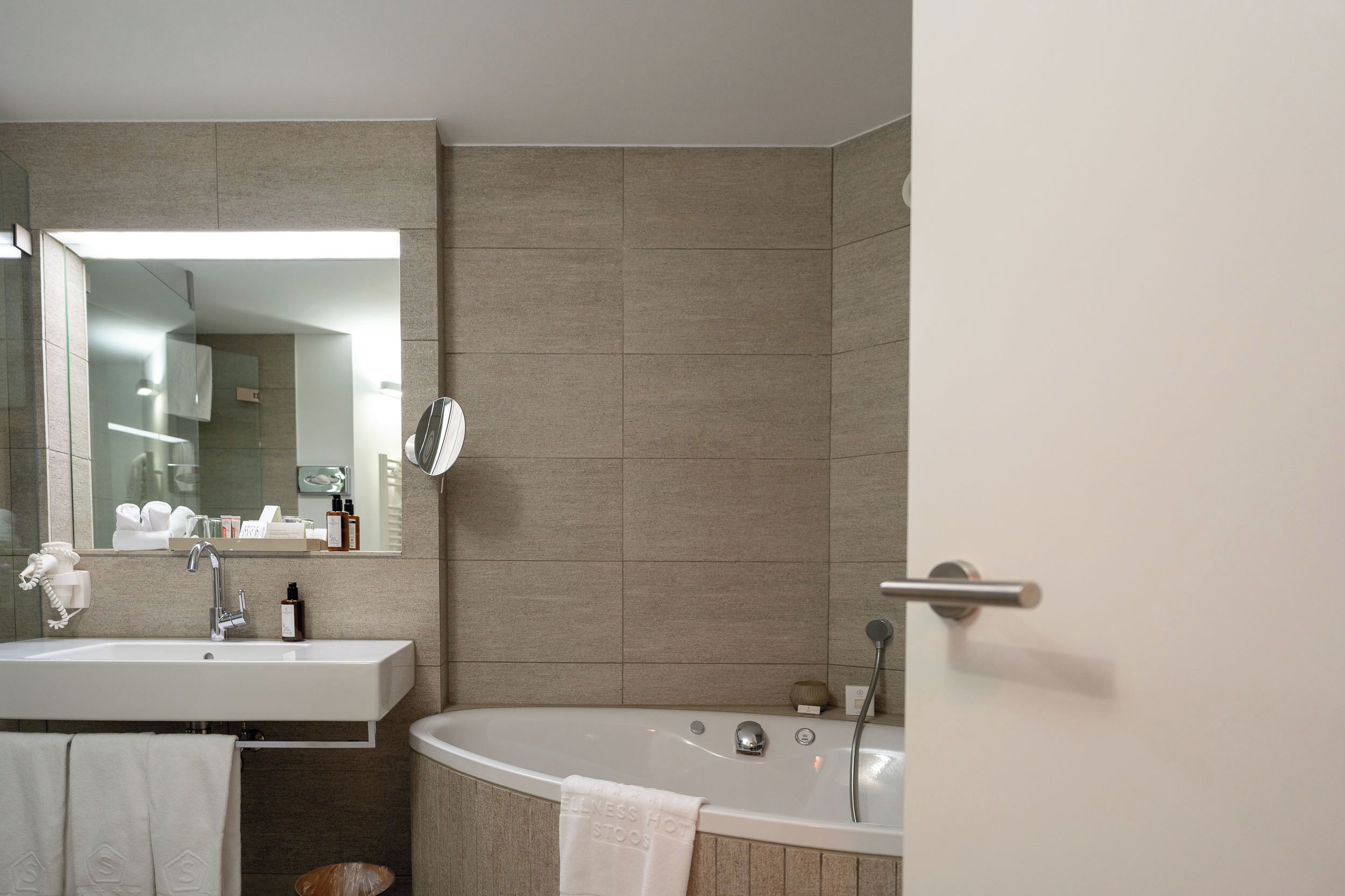 A bathroom with a sink, mirror, and bathtub.