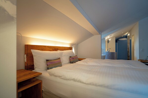 A bedroom with a large bed, wooden headboard, bedside tables, and a walk-in closet.