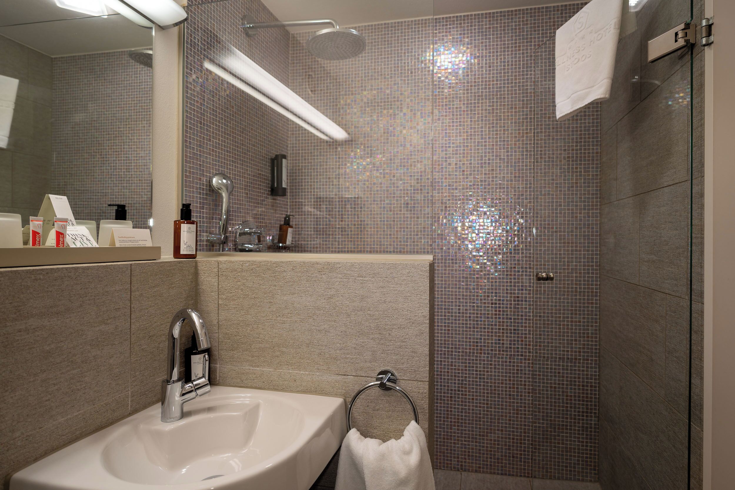 Un baño moderno con lavamanos, espejo y ducha.