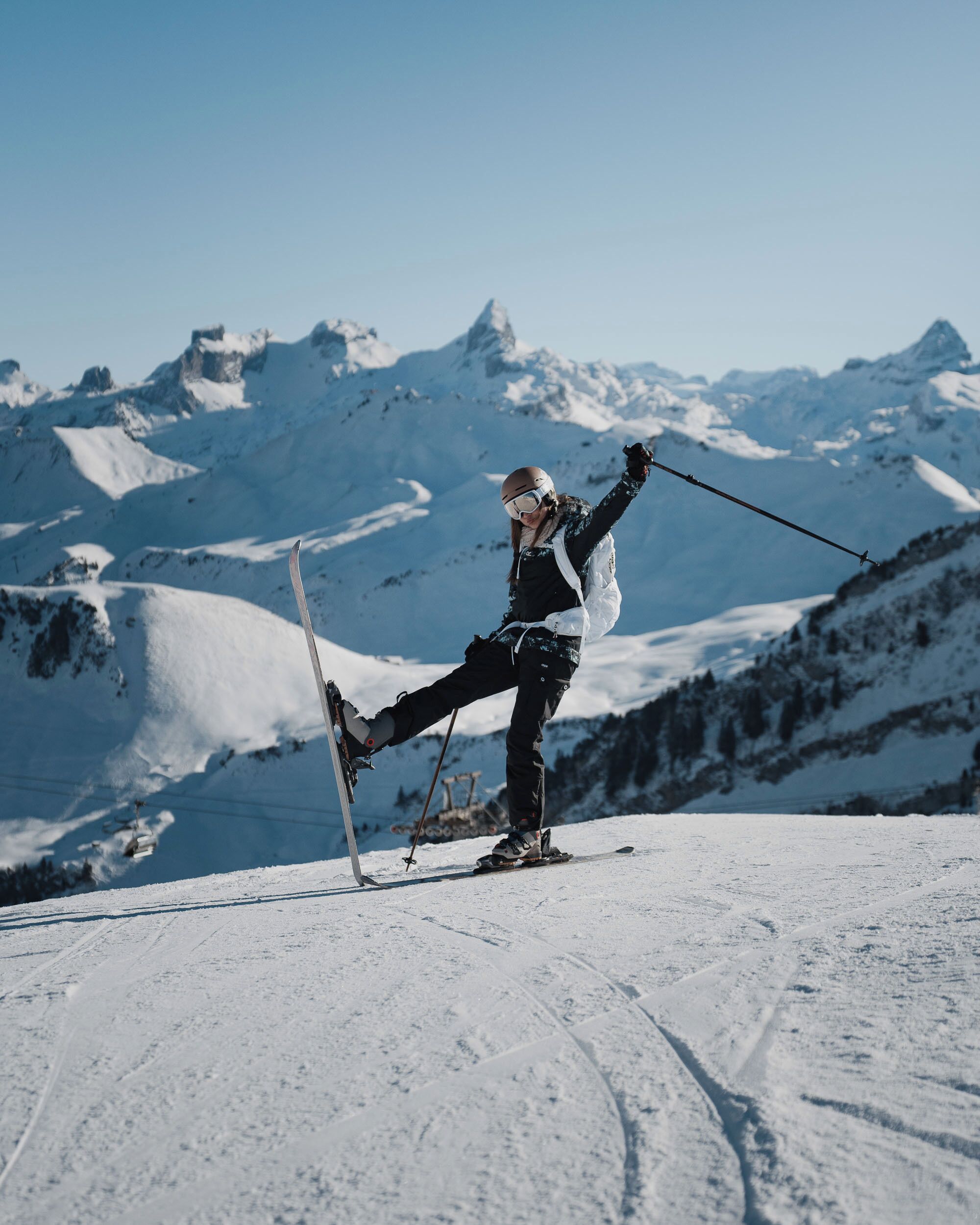 Eine Person fährt Ski auf einem verschneiten Hang vor einer Bergkulisse.