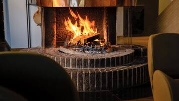 Una chimenea con un marco de piedra y una cubierta metálica, con llamas visibles en su interior.