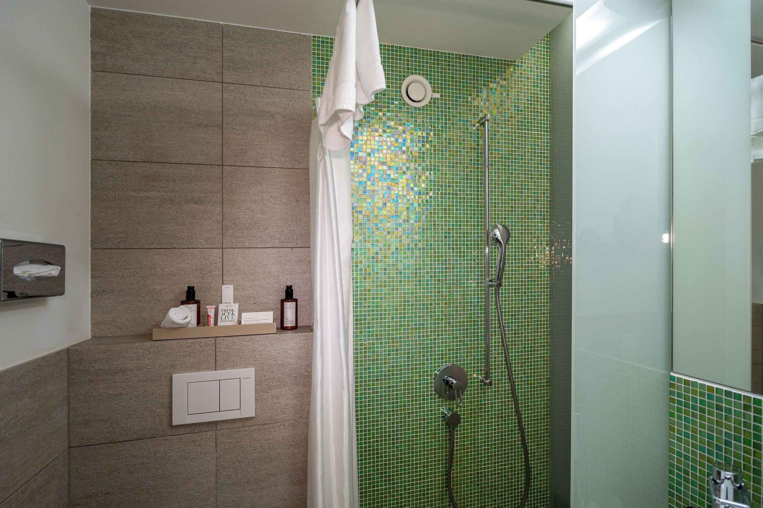 Un baño moderno con ducha, toallero y estante con artículos de aseo.