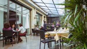 An indoor dining area with tables and chairs, a glass ceiling, and potted plants. - Hotel Bardo Recoletos Coco (Salamanca)