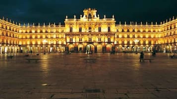 A large, illuminated courtyard with a grand building featuring multiple arches and a central entrance.