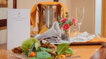 A table set with a menu, a vase with flowers, a glass of champagne, and a decorative pitcher.