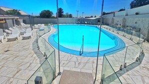 A swimming pool with a glass enclosure, surrounded by lounge chairs and a tiled deck. - Hotel Bardo Recoletos Coco (Salamanca)