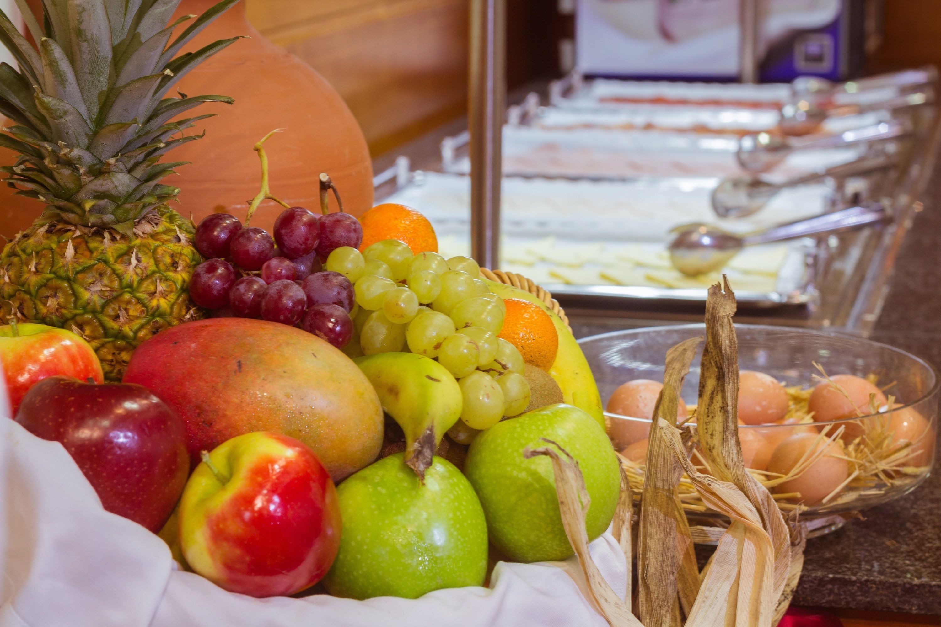 A fruit and egg display with a variety of fruits including apples, grapes, oranges, and a pineapple.