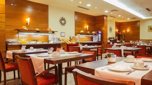 A restaurant with wooden panel walls, multiple tables with white tablecloths, and orange chairs. - Hotel Bardo Recoletos Coco (Salamanca)