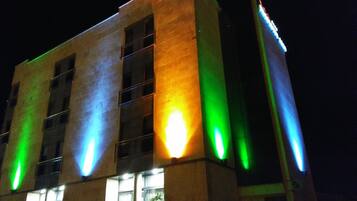 Un edificio con tiras verticales iluminadas en verde, amarillo y azul.