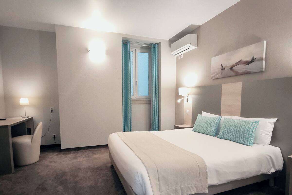 A modern bedroom with a large bed, a desk, and a chair.