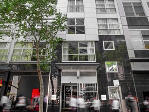Um edifício moderno com várias janelas, uma árvore na frente e uma placa indicando 'mantra 100'.