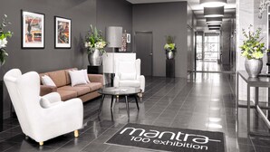Un espace d’accueil moderne comprenant un canapé, des fauteuils, une table basse et des œuvres d’art accrochées aux murs.