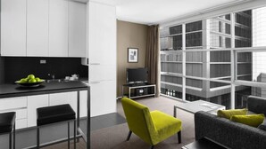 Un salon moderne avec un canapé, un fauteuil vert vif et un téléviseur.