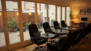 Un espace de détente intérieur moderne, avec des portes vitrées donnant sur un patio extérieur.