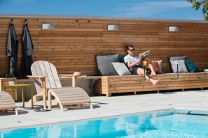 A poolside area with wooden loungers, a wooden deck, and a pool.