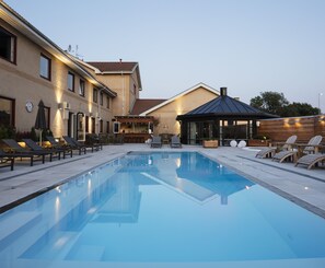 A swimming pool with lounge chairs and a bar area.