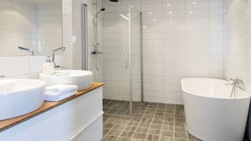 A modern bathroom with a large sink, a bathtub, and a glass-enclosed shower.