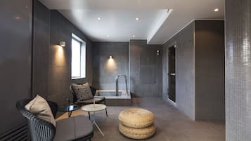 Relax in a serene space with a wicker chair, round table, and a large bathtub.