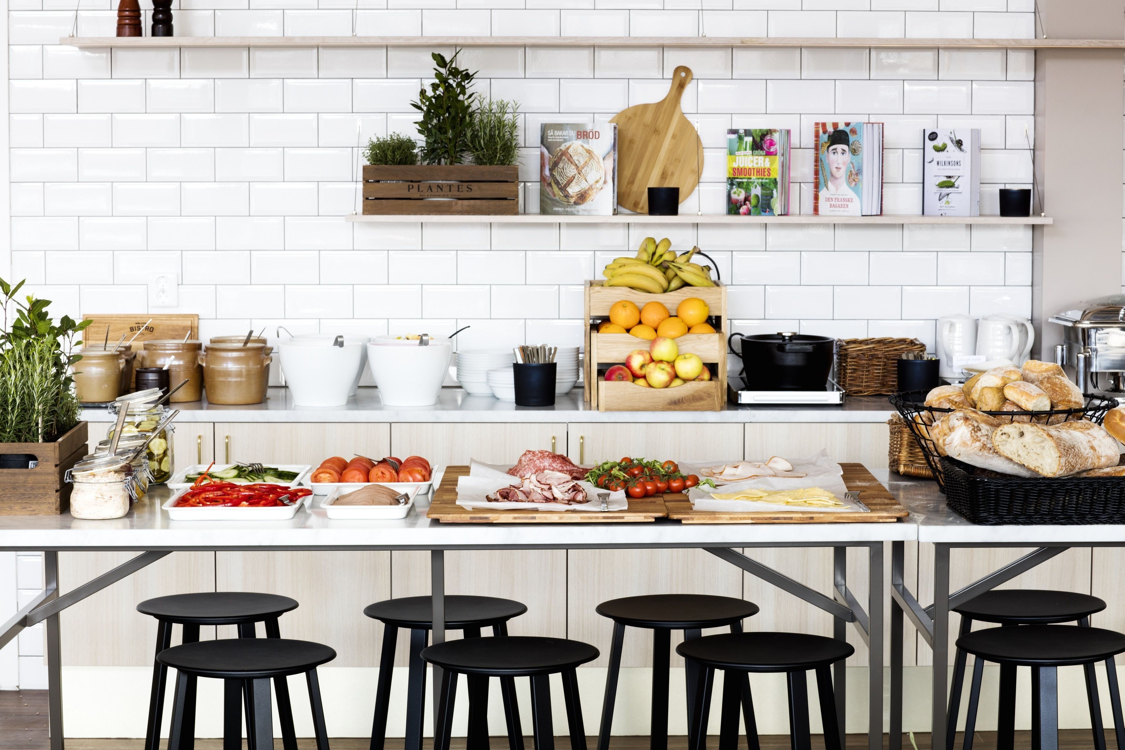 Une cuisine moderne avec des carreaux blancs, des étagères en bois et divers produits alimentaires.