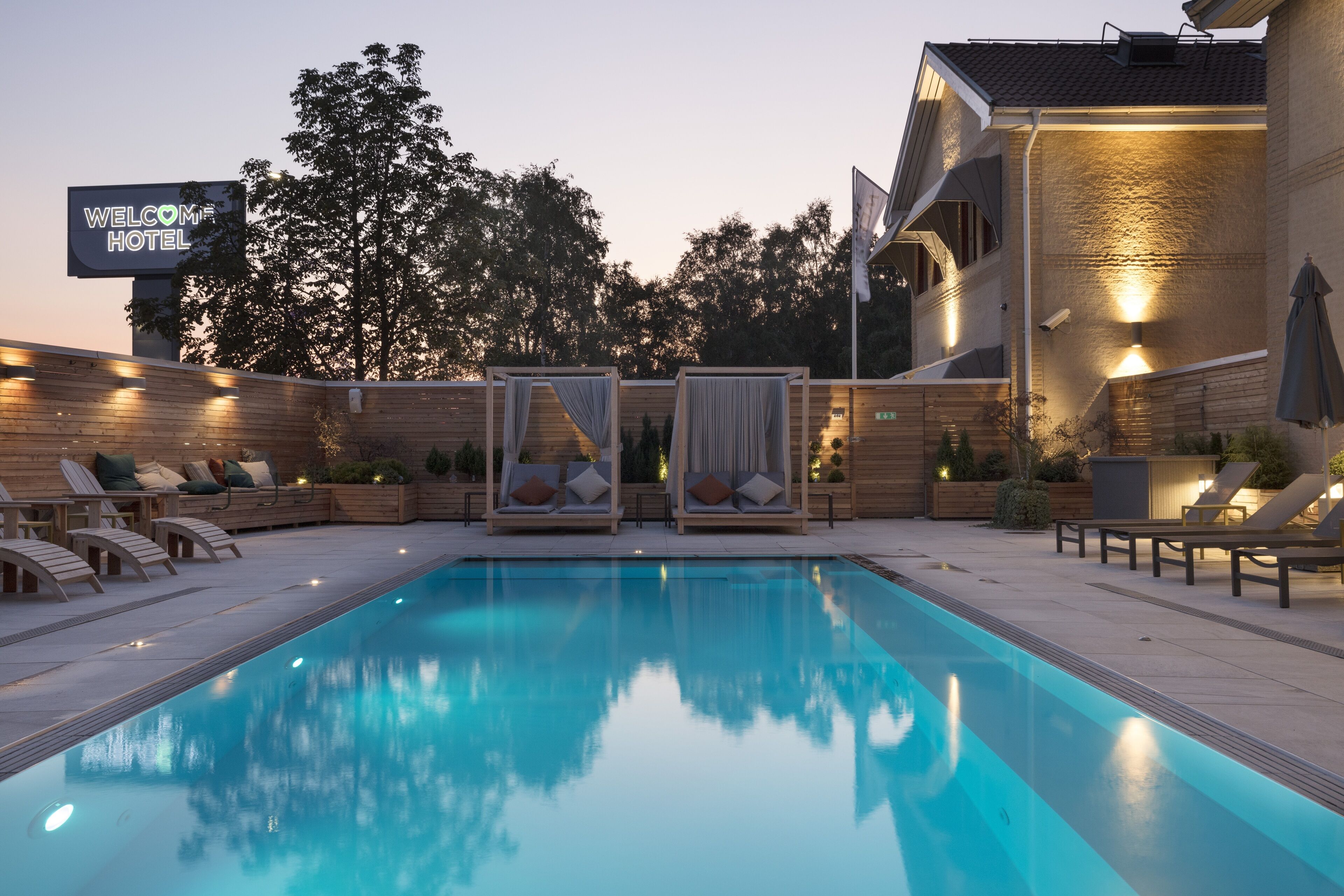Una piscina con sillas de descanso y un letrero que dice "WELCOME HOTEL".