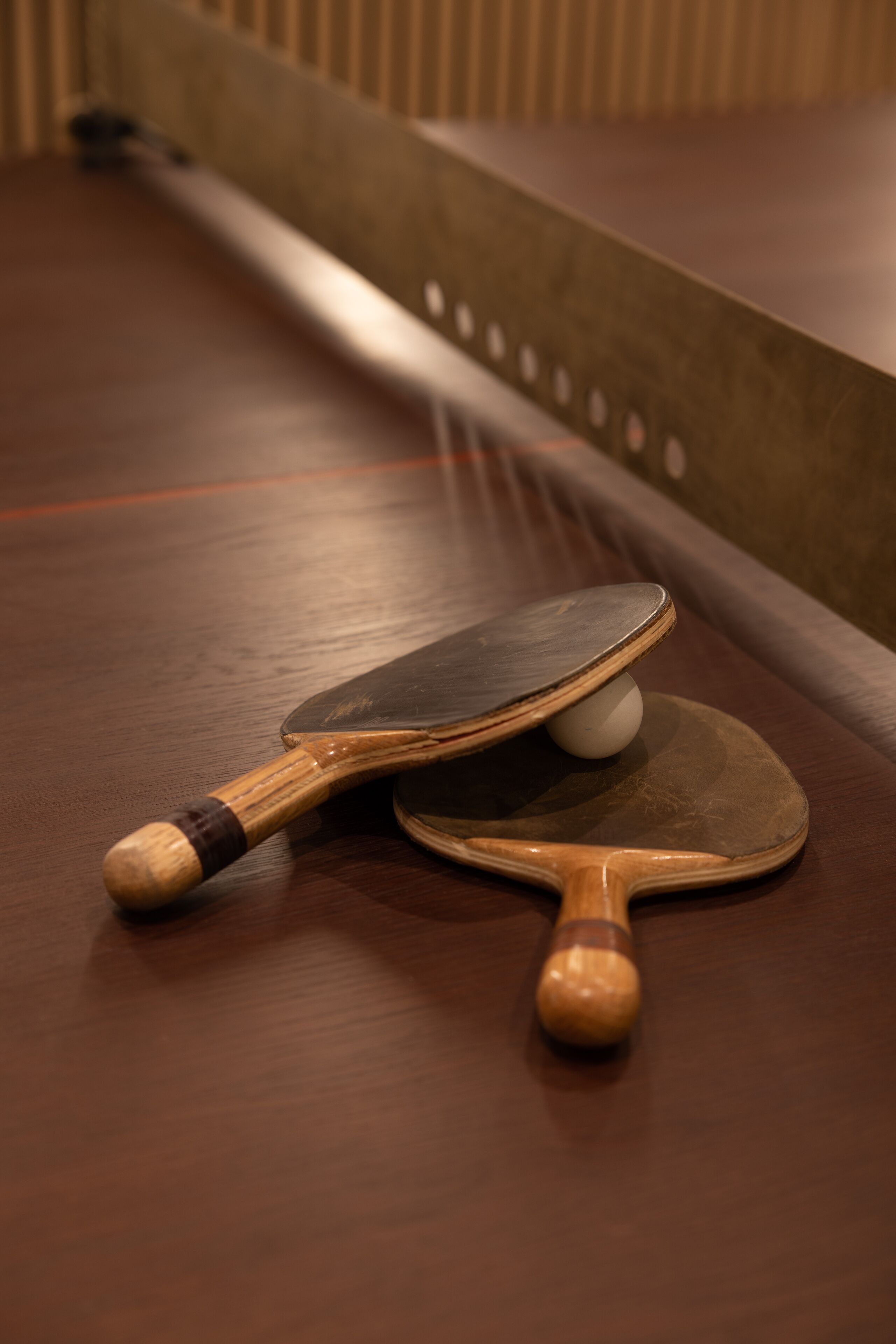 A table with two ping pong paddles and a ball.