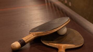 A table with two ping pong paddles and a ball.