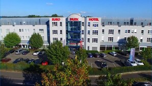 A hotel with "EURO PARK HOTEL" signage, a parking lot, and surrounding greenery.