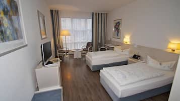 Una habitación de hotel con dos camas, un escritorio, una silla, un televisor y una lámpara.