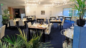 A restaurant with multiple dining tables, chairs, and hanging light fixtures.