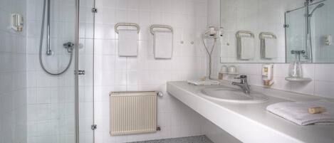 A modern bathroom with a glass shower enclosure, a double sink vanity, and a large mirror.