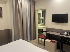 Una camera d'albergo con un letto, una scrivania con una sedia, una televisione e un angolo cottura.